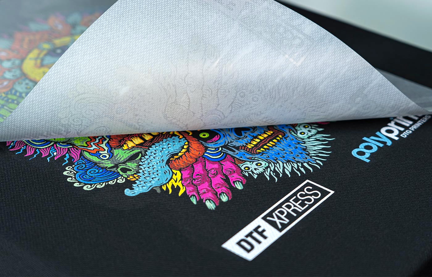 Colourful design transferred on garment showing DTF film peel off 